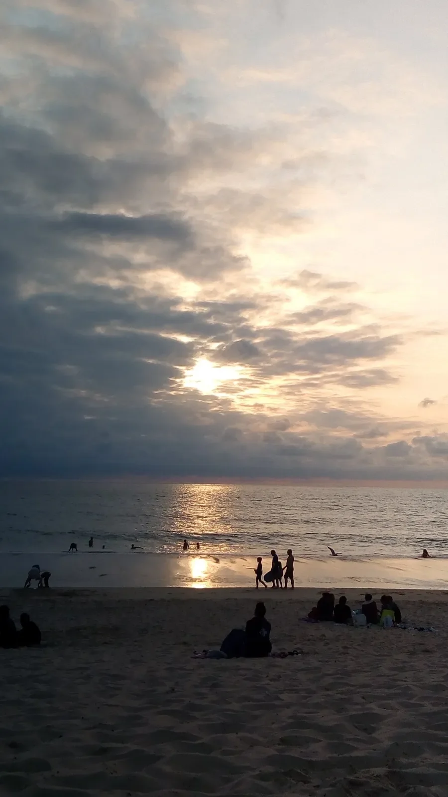 Le soleil perce les nuages au-dessus de l'océan à Capbreton et se reflète sur le sable mouillé.