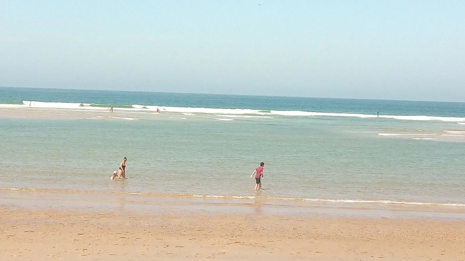 Sur la plage de Santocha à Capbreton, des baigneurs dans l'eau claire, avec les vagues qui déferlent au large.