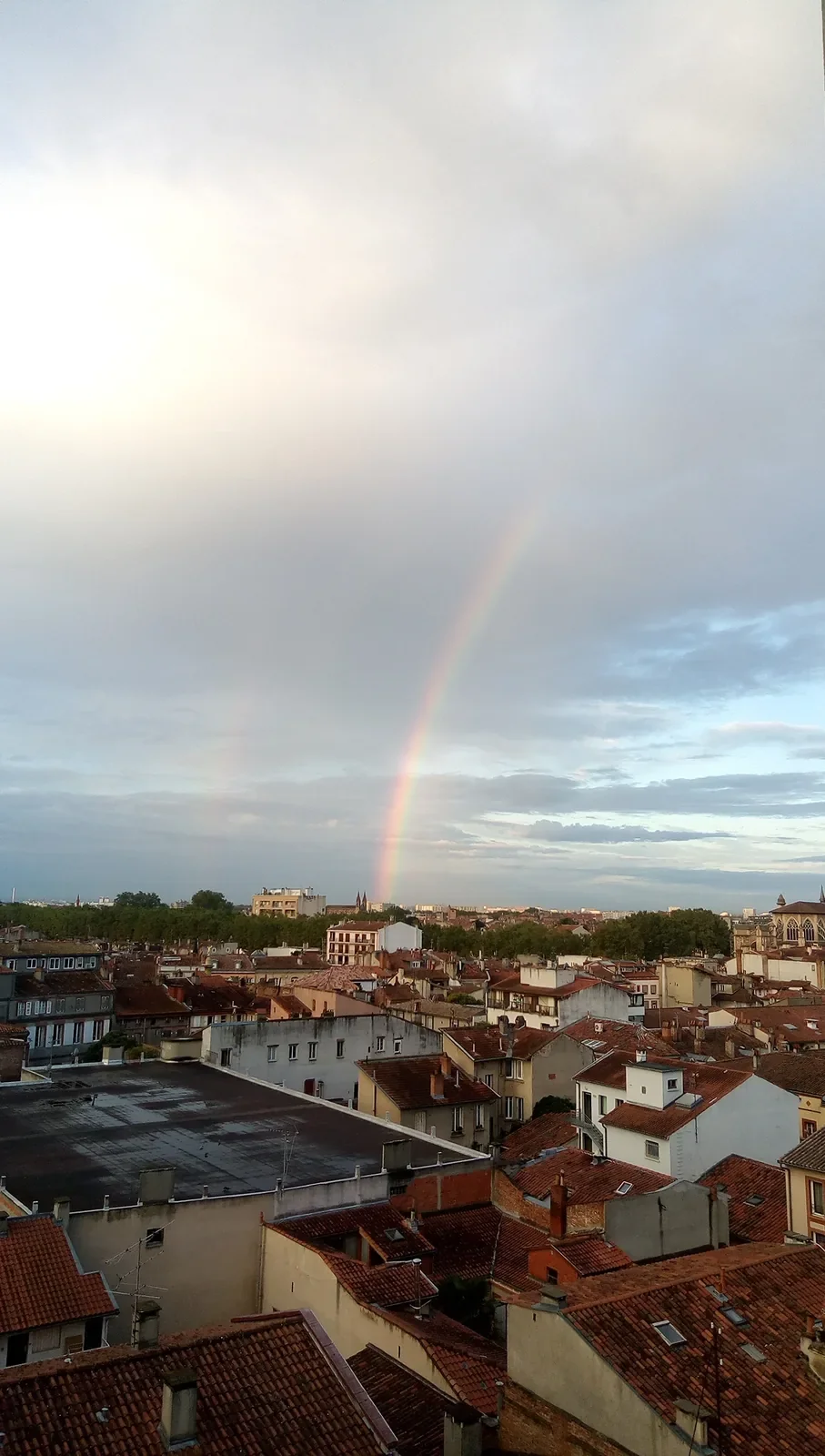 Un arc-en-ciel au-dessus des toits de tuiles de Toulouse, vu depuis le septième ciel.