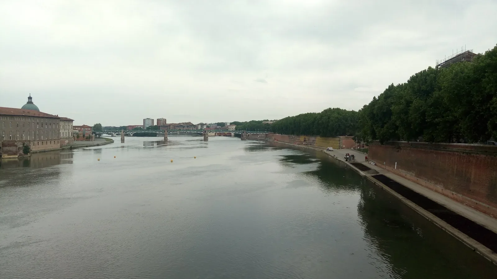 La Garonne vue depuis le pont, à Toulouse, avec le dôme de La Grave et un pont au loin sous un ciel gris.