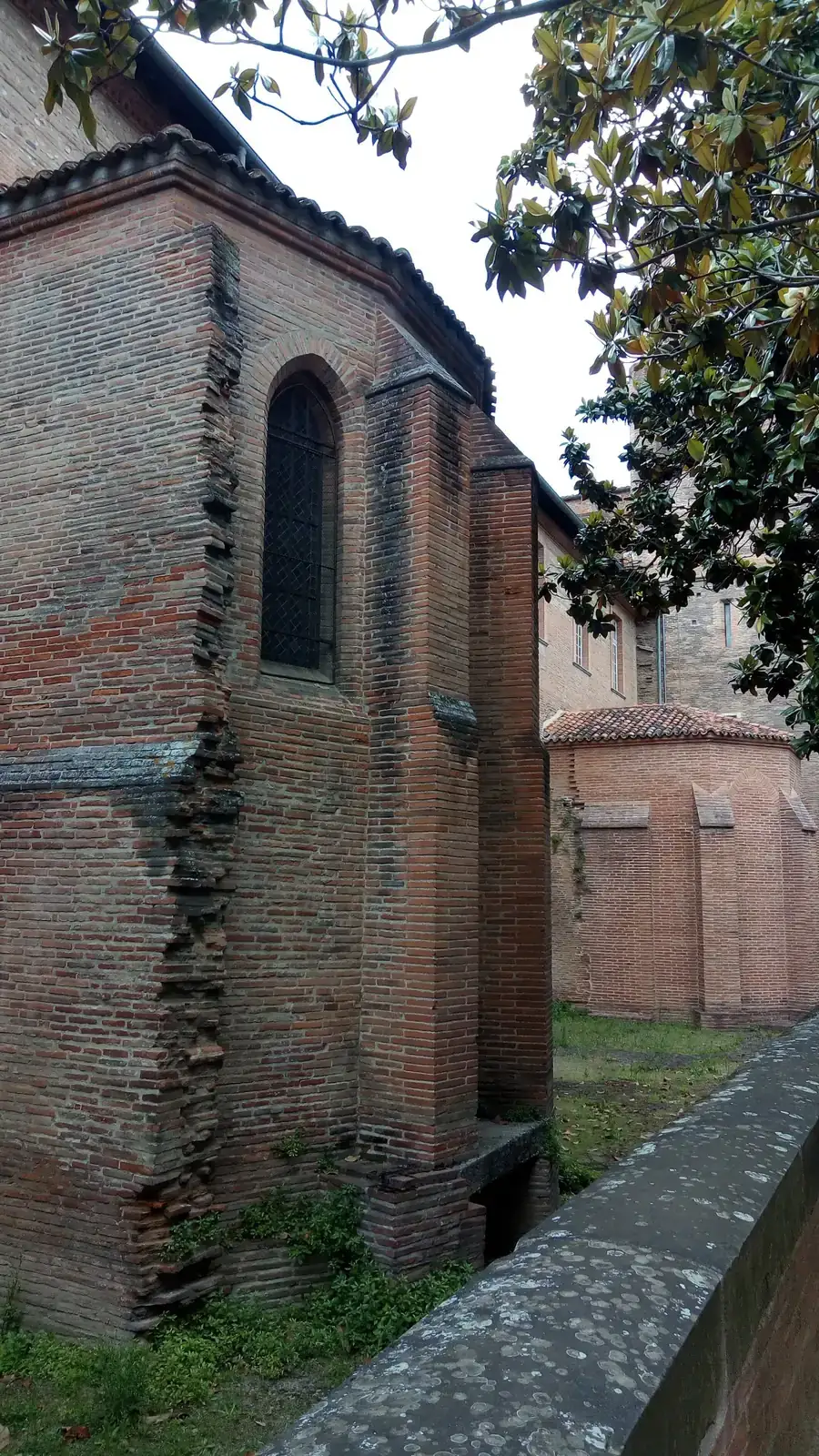Un mur de brique rose du musée des Augustins, à Toulouse, avec sa haute fenêtre en arc et ses contreforts