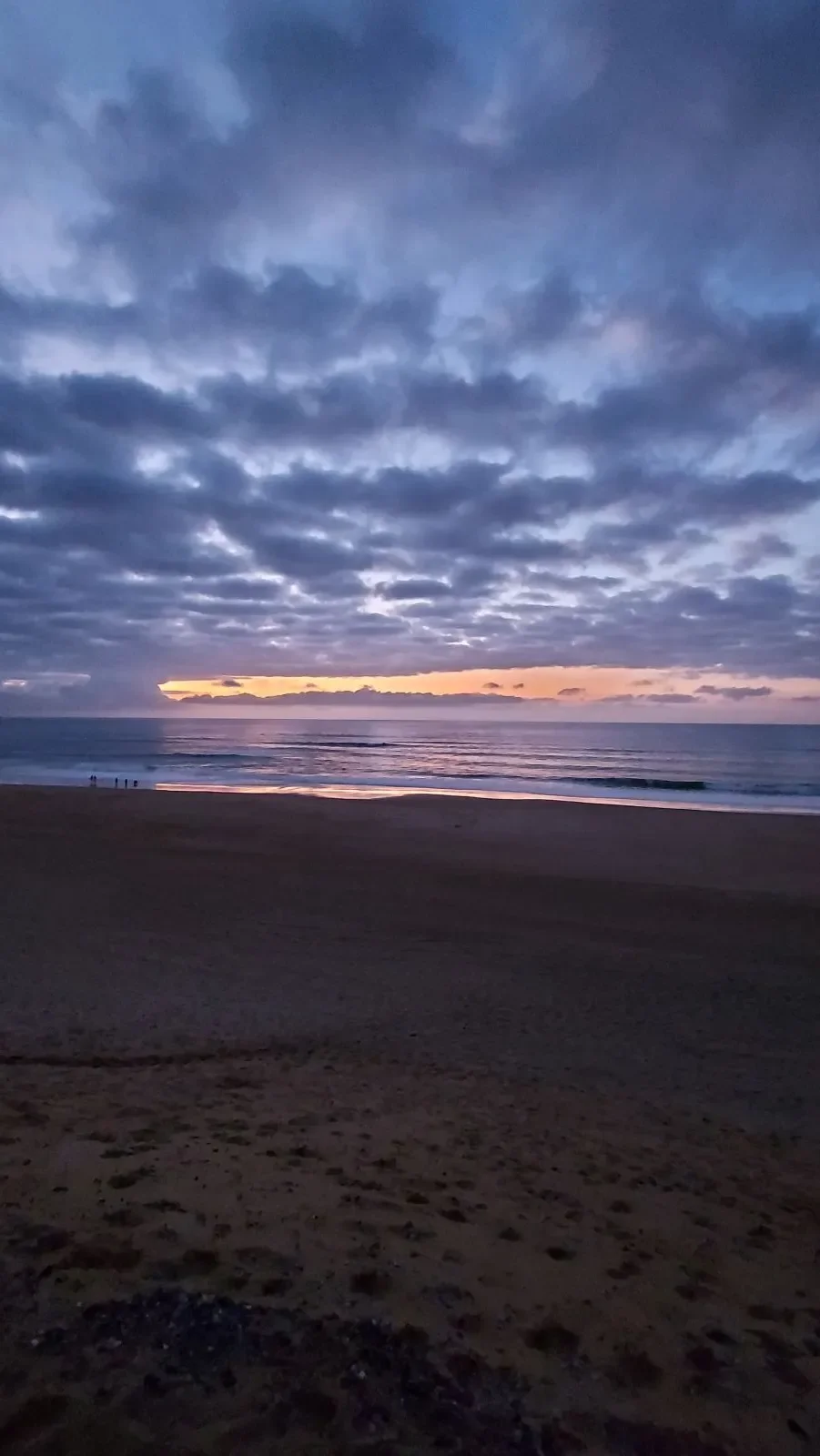 Une trouée orange sous un ciel de gros nuages bleus, au crépuscule, sur l'océan à Capbreton.