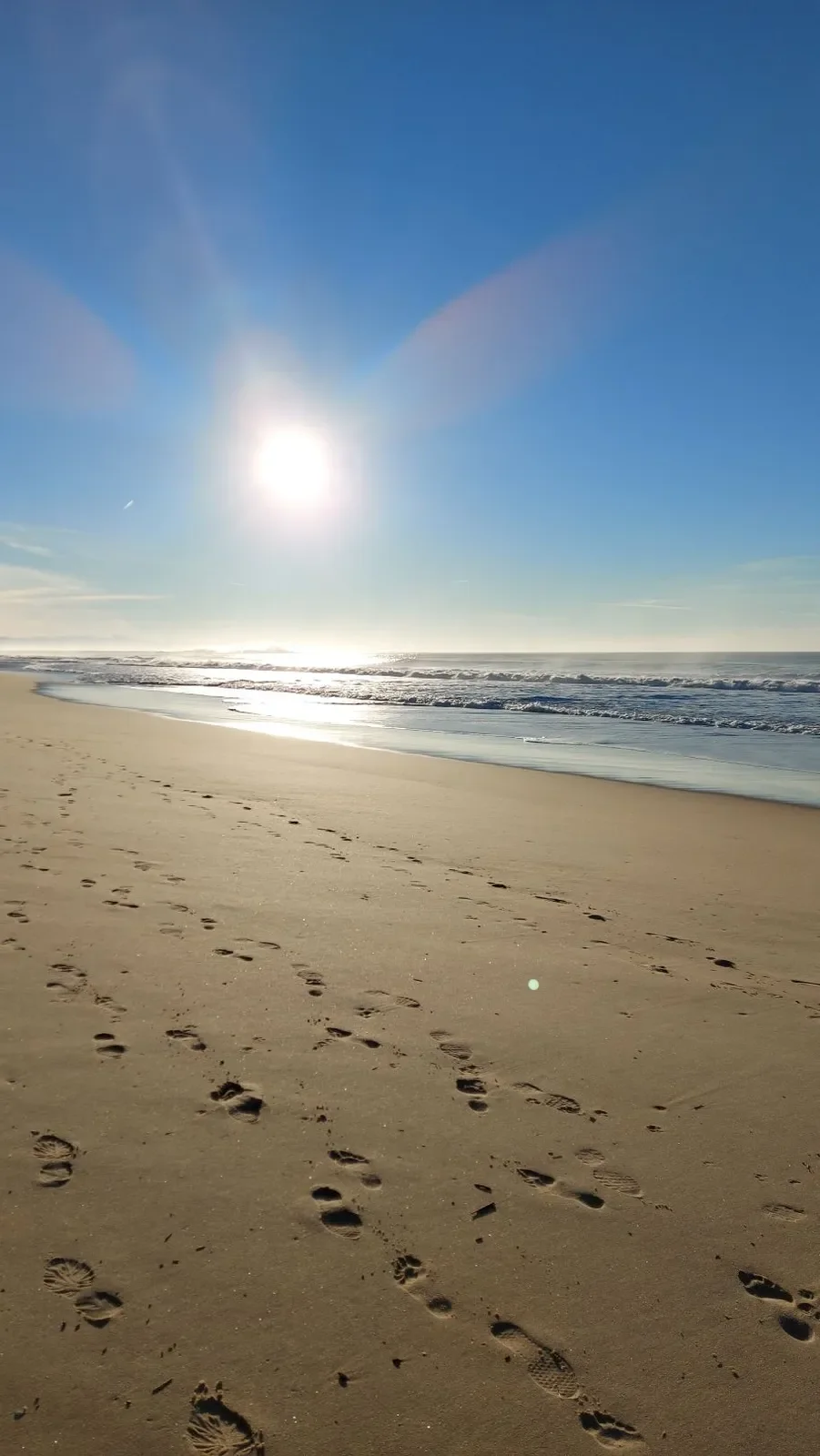  Le soleil en contre-jour sur la plage de Capbreton, avec des traces de pas dans le sable et l'océan qui scintille au loin, le 31 décembre 2021.