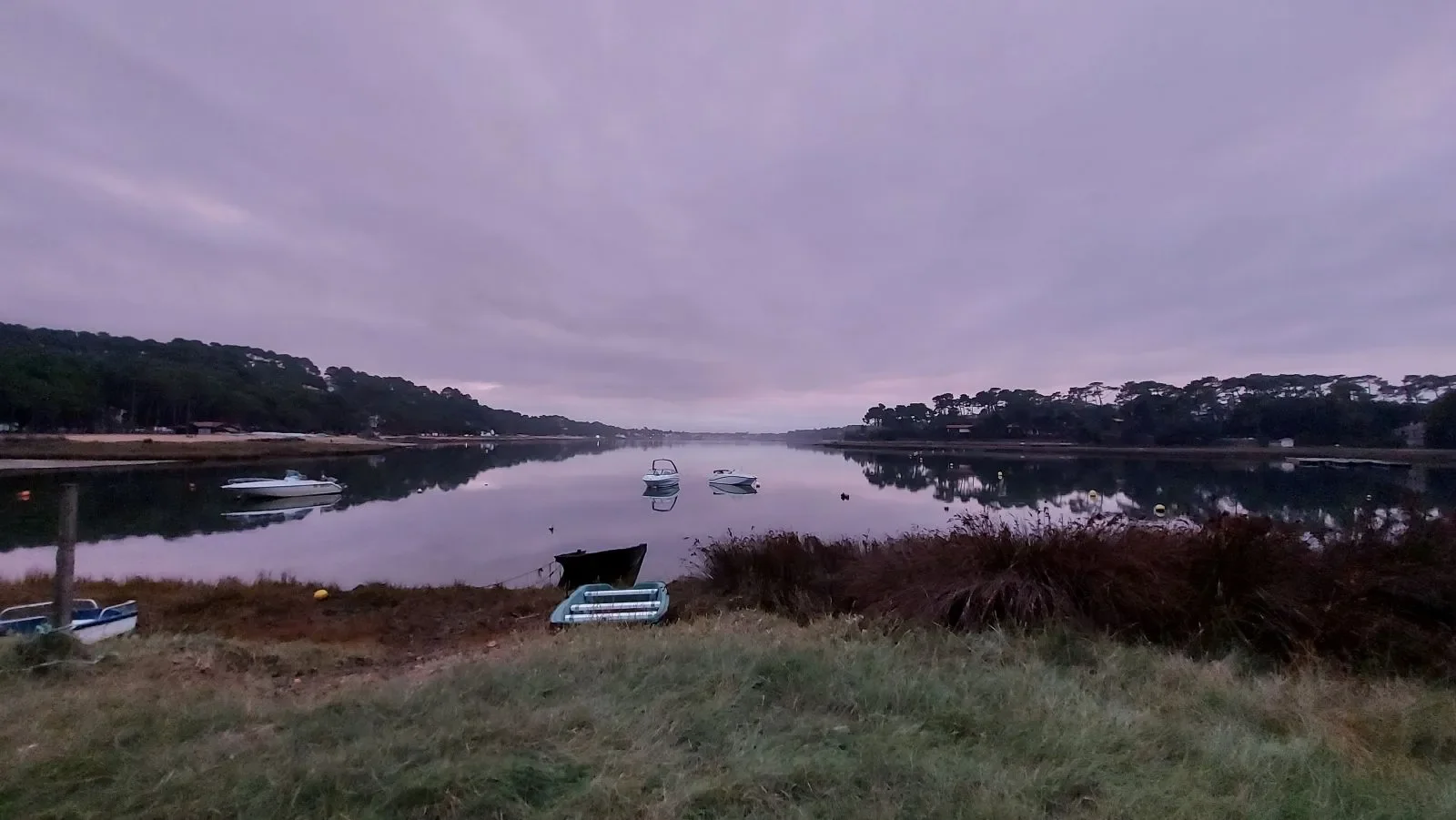 Des bateaux amarrés se reflètent dans le lac marin d'Hossegor, sous un ciel violet au crépuscule, en novembre 2021.