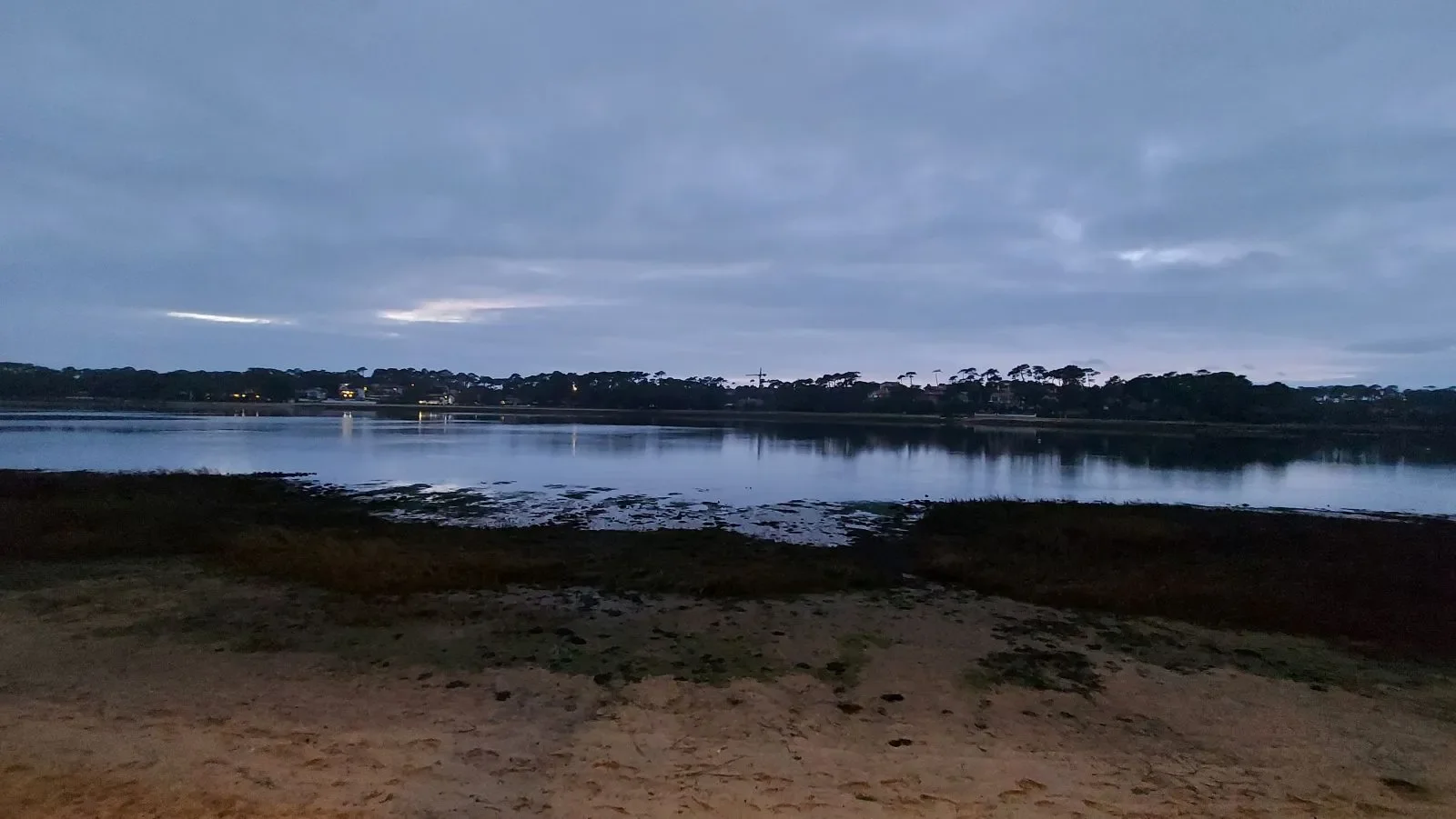 À l'heure bleue, les lumières des maisons s'allument de l'autre côté du lac marin d'Hossegor.