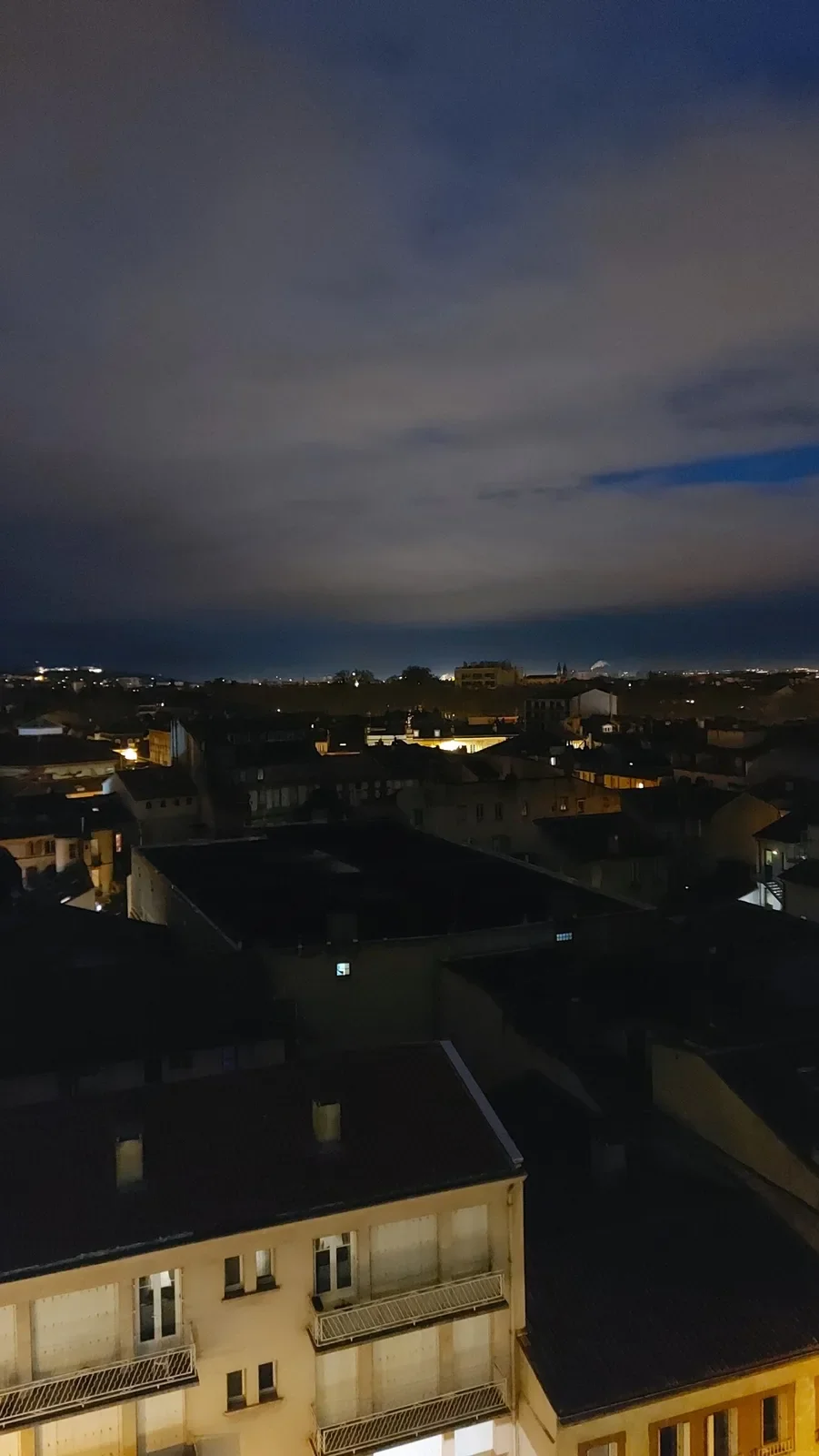 Toulouse la nuit sous de gros nuages bleu foncé, avec une trouée de ciel clair