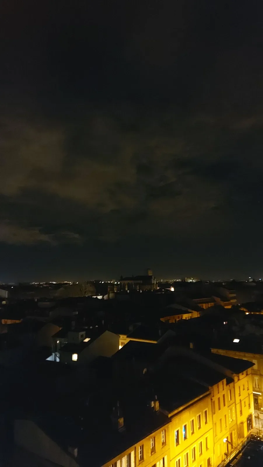 Façades de brique éclairées en jaune dans une rue de Toulouse au matin.