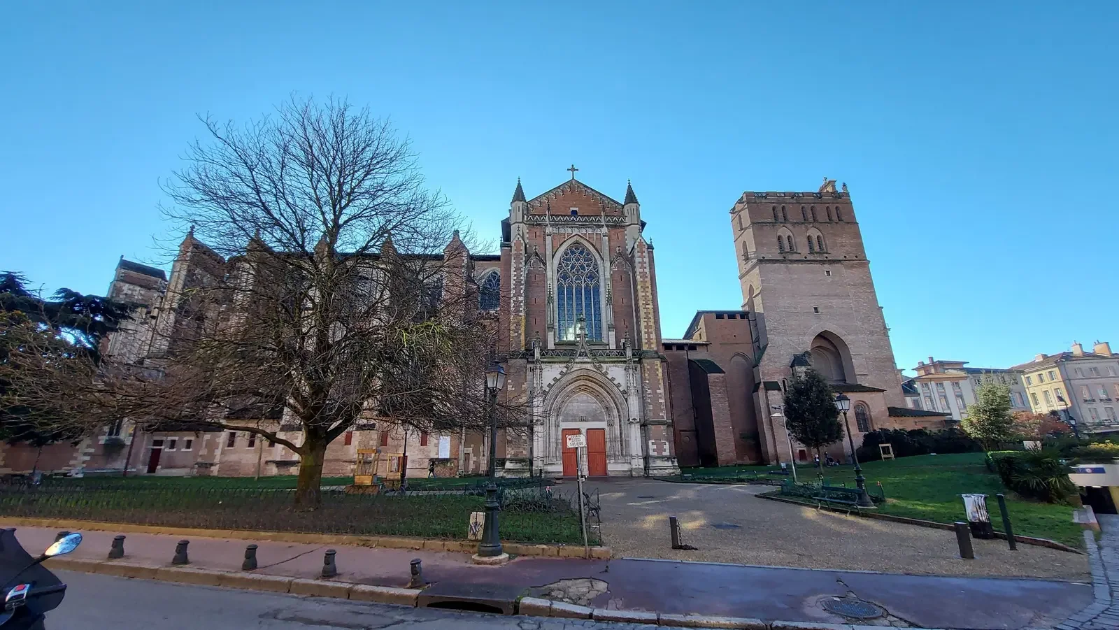 Façade gothique en brique de la cathédrale Saint-Étienne de Toulouse, avec sa grande tour, sous un ciel bleu