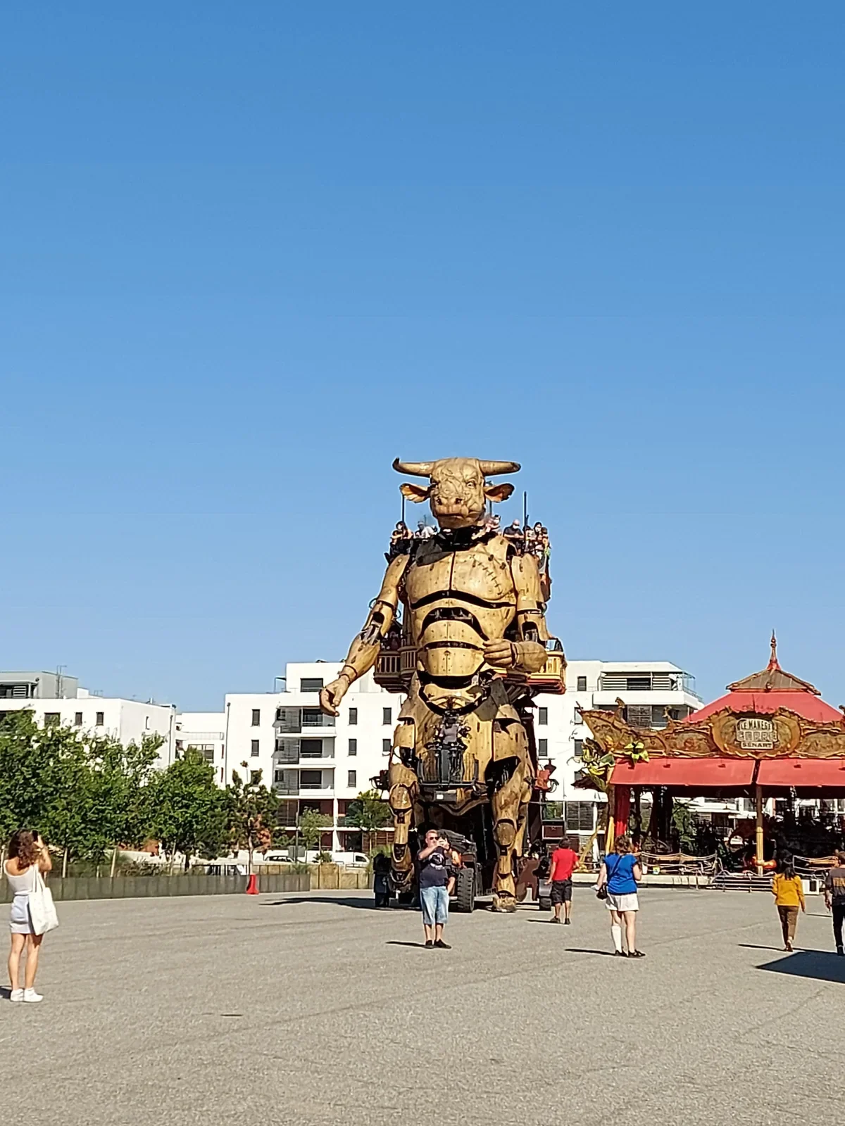 Le Minotaure géant de la Halle de la Machine, à Toulouse, avec le manège Carré Sénart à droite, sous un ciel bleu