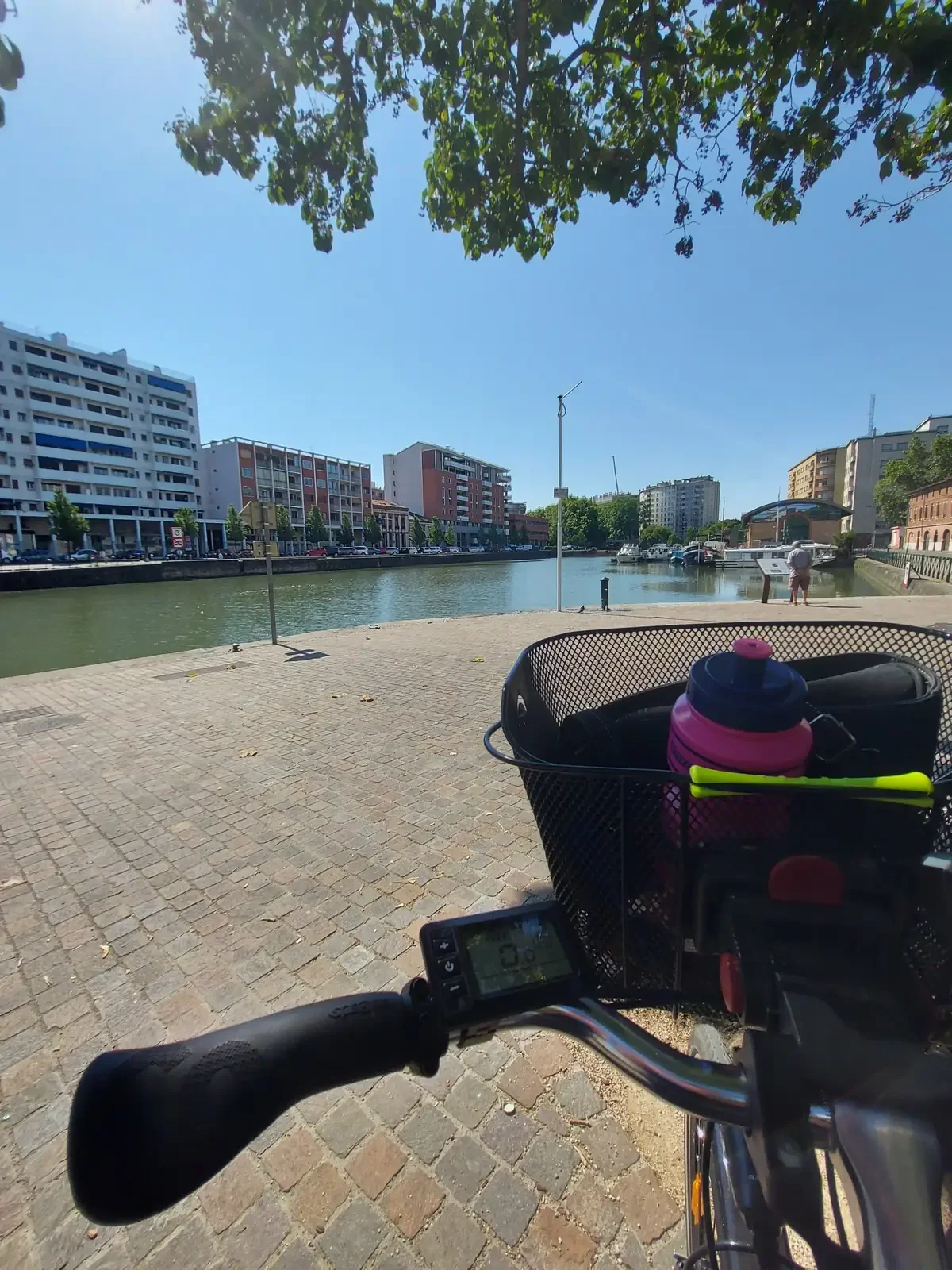 Port Saint Sauveur, canal du Midi à Toulouse, vu depuis un quai pavé avec le guidon d'un vélo au premier plan et des péniches au fond