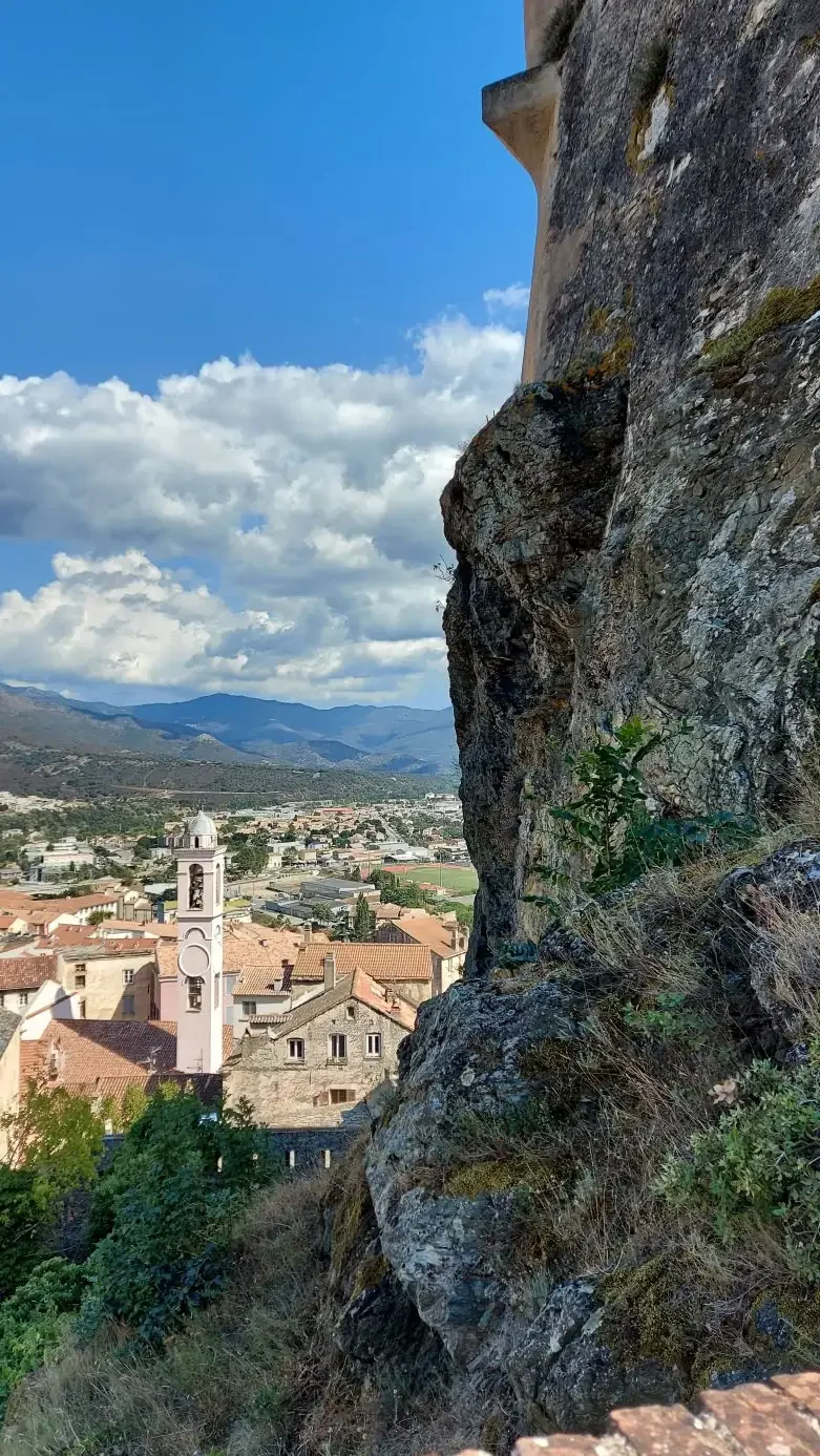 Du haut du rocher, le clocher et les toits de la vieille ville, avec la montagne en fond.