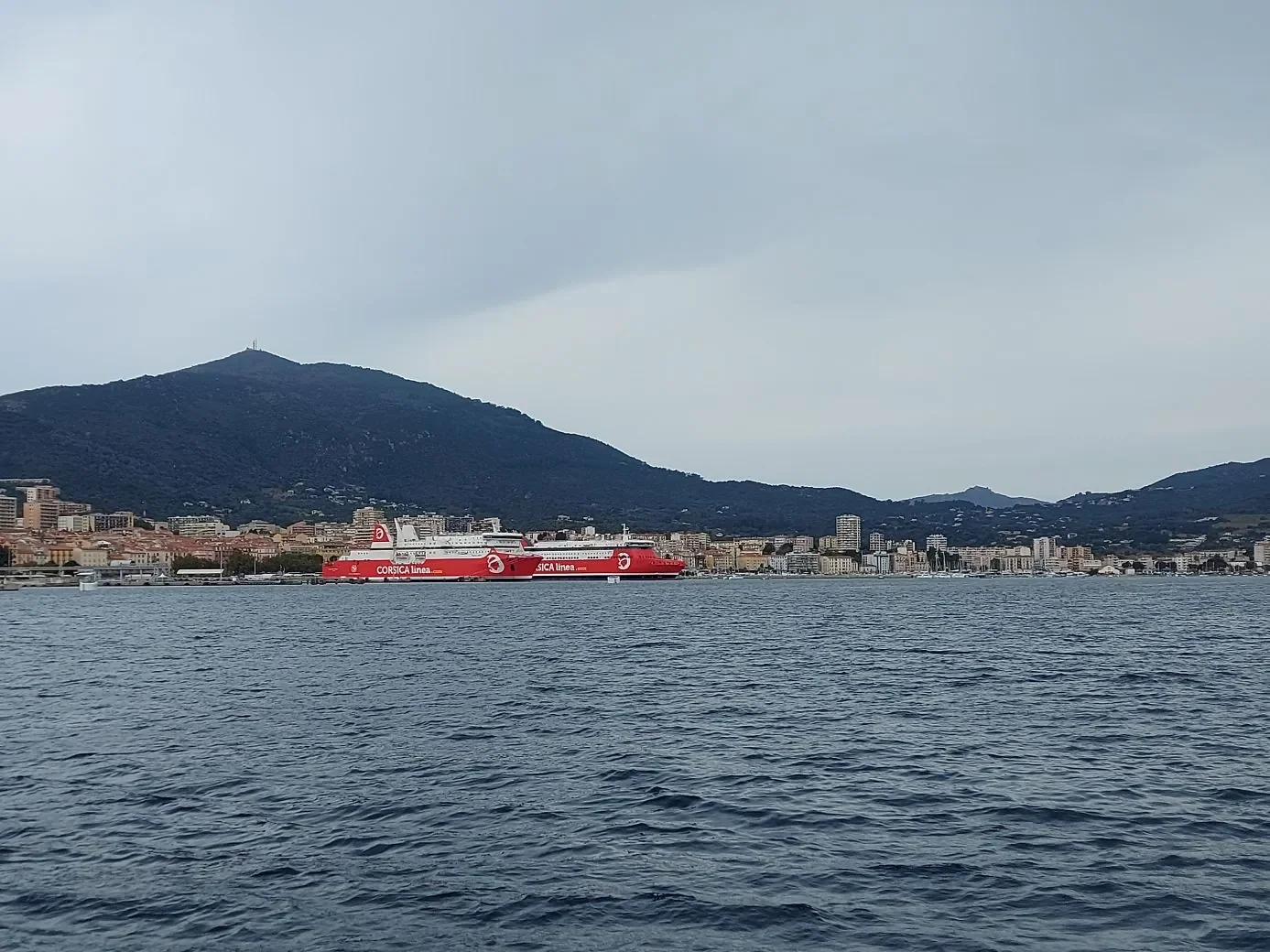 Le port d'Ajaccio vu depuis l'eau, avec les ferries et la ville adossée à la colline.